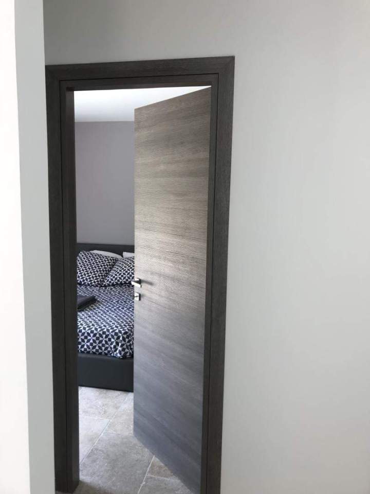 Installation de porte intérieure battante moderne dotée d'un panneau à veinage horizontal texturé Porto-Vecchio