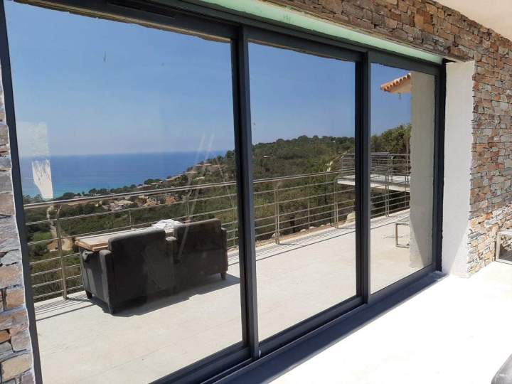 Grande baie vitrée coulissante en aluminium à trois vantaux avec un vitrage réfléchissant Porto-Vecchio