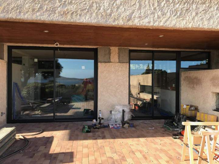 Des baies vitrées coulissantes en aluminium noir installées sur une terrasse en cours de finition Porto-Vecchio