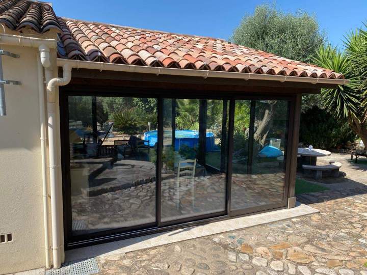 Baie vitrée coulissante à cadre sombre installée sur une terrasse extérieure Porto-Vecchio